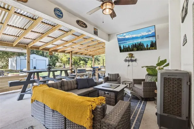 a living room with furniture a flat screen tv and floor to ceiling window