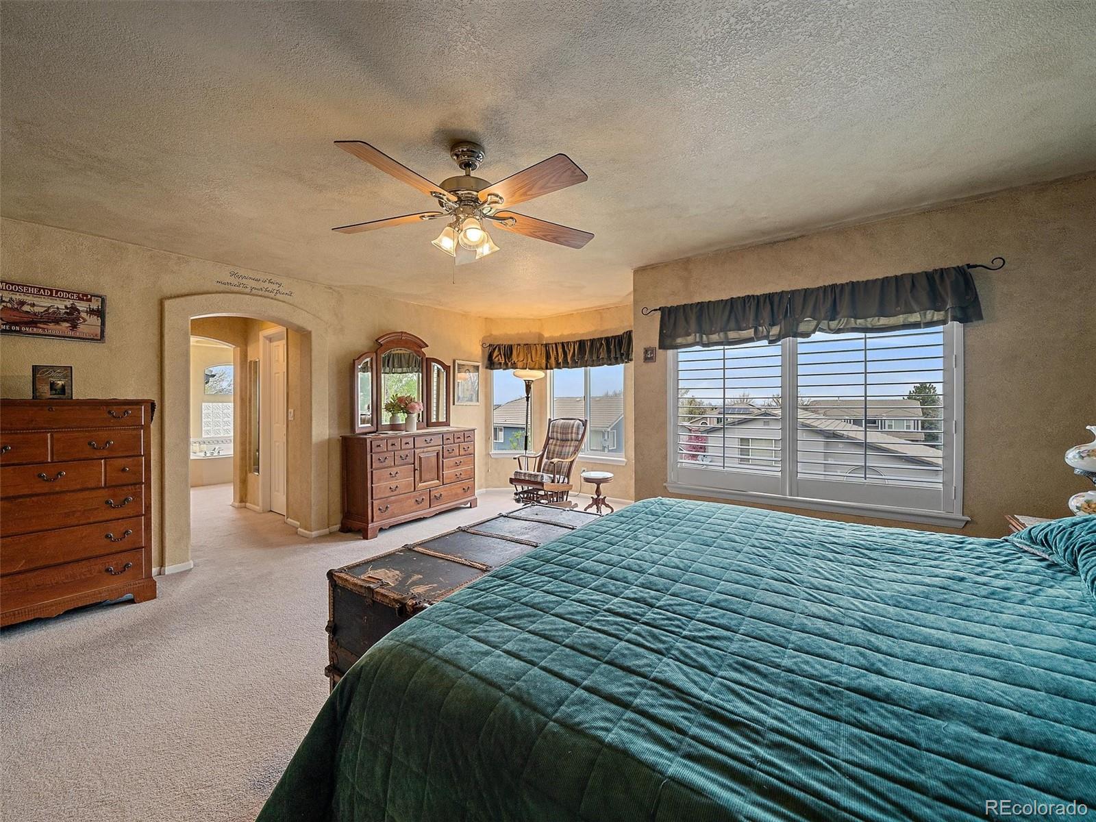 6523 Shannon Trail Highlands Ranch, CO 80130 - Photo 21 of 38 a spacious bedroom with a large bed a chandelier and windows