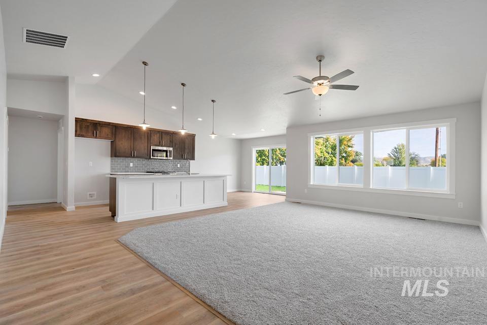 1340 Dawn Street Weiser, ID 83672 - Photo 7 of 32 Kitchen featuring light countertops, an island with sink, hanging light fixtures, decorative backsplash, and dark brown cabinets