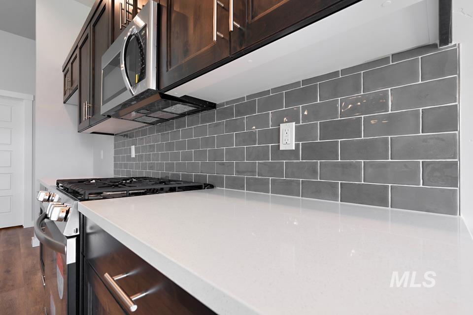 1340 Dawn Street Weiser, ID 83672 - Photo 9 of 32 Kitchen with appliances with stainless steel finishes, dark brown cabinetry, tasteful backsplash, and light stone counters