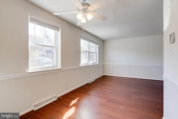 an empty room with wooden floor windows and fan