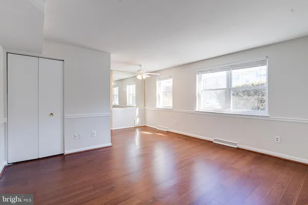 an empty room with wooden floor and windows