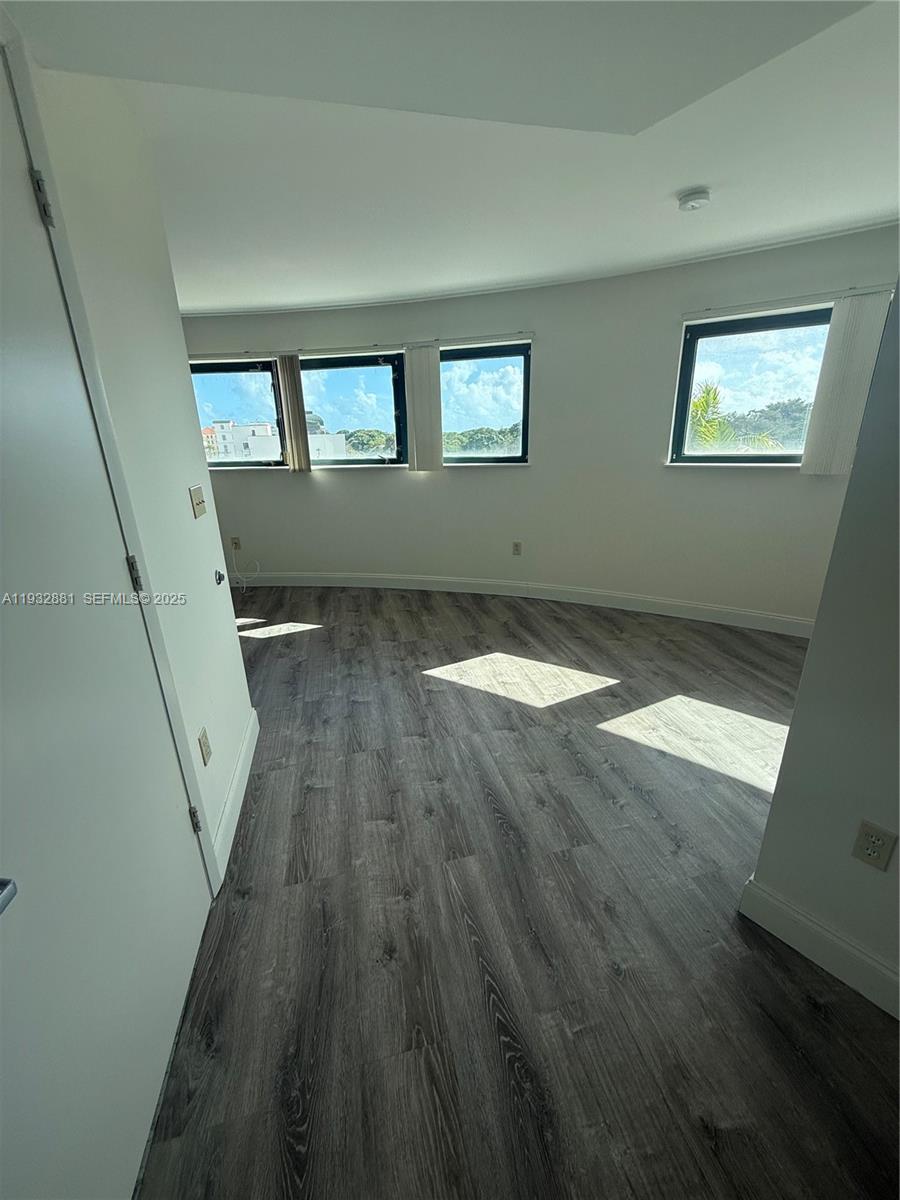 5725 Southwest 72nd Street, Unit 5725 Miami, FL 33143 - Photo 2 of 5 a view of an empty room with wooden floor and a window