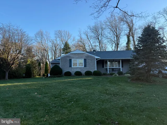 a front view of a house with a garden and trees