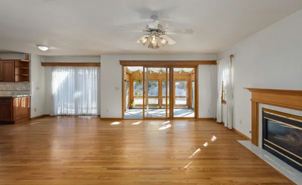 an empty room with wooden floor chandelier fan and windows