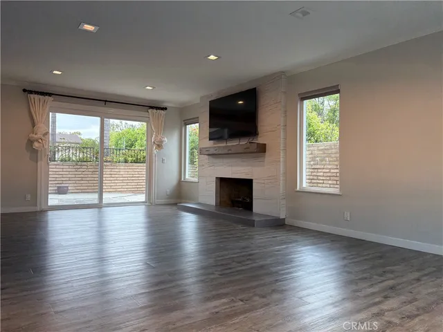 an empty room with wooden floor fireplace and windows