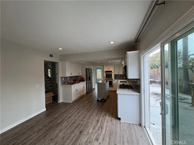 a kitchen with a refrigerator and wooden floor