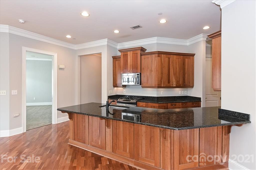 626 Queens Road, Unit 203 Charlotte, NC 28207 - Photo 22 of 48 a kitchen with stainless steel appliances granite countertop a stove a sink and a refrigerator with wooden floor