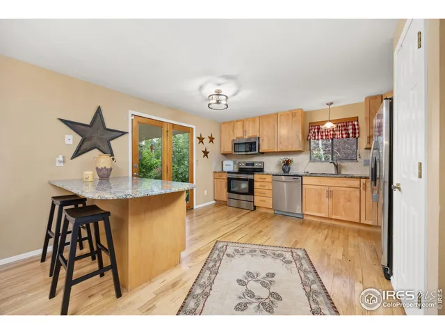 a kitchen with stainless steel appliances granite countertop a stove top oven a sink a dining table and chairs with wooden floor