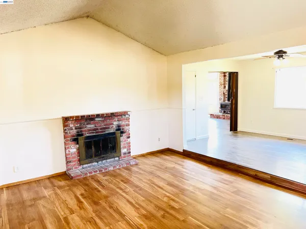 a view of empty room with a fireplace and wooden floor