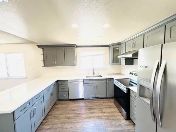 a large kitchen with stainless steel appliances granite countertop a sink and dishwasher a refrigerator with wooden cabinets