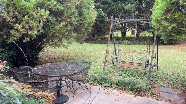 a view of backyard with table and chairs and a large tree