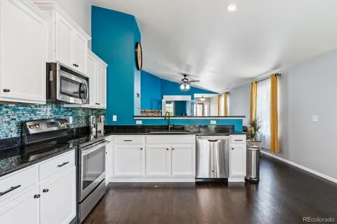 a kitchen with stainless steel appliances granite countertop wooden cabinets a sink a stove a dining table and chairs