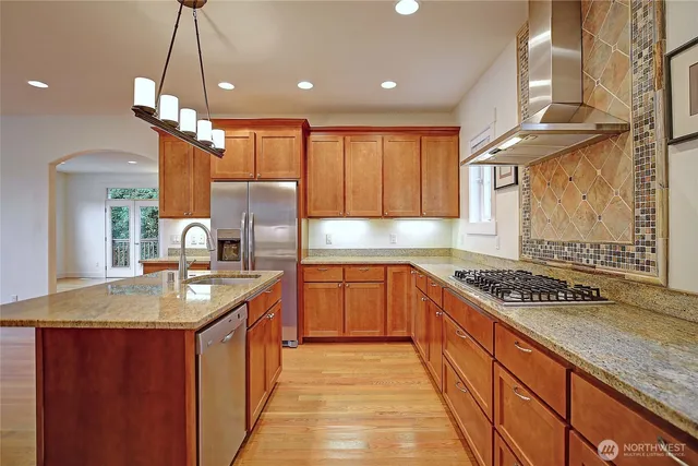 a kitchen with stainless steel appliances granite countertop a sink a stove and a refrigerator