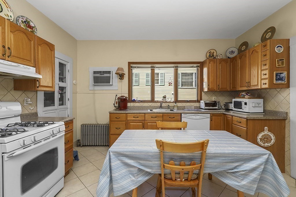 61 Everett Street Everett, MA 02149 - Photo 5 of 19 a kitchen with stainless steel appliances granite countertop a stove a sink dishwasher and a refrigerator with wooden cabinets