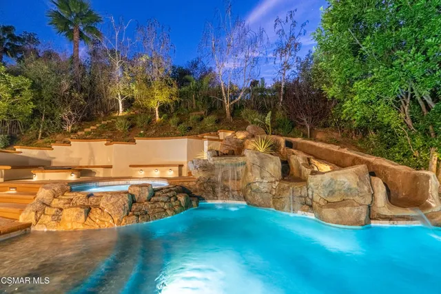 a view of a house with backyard water fountain and sitting area