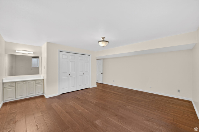 3120 North Apache Way Provo, UT 84604 - Photo 42 of 58 Spacious room featuring wood-finish flooring, a built-in vanity with cabinetry and countertop, an integrated mirror with sconce lighting, and bi-fold closet doors