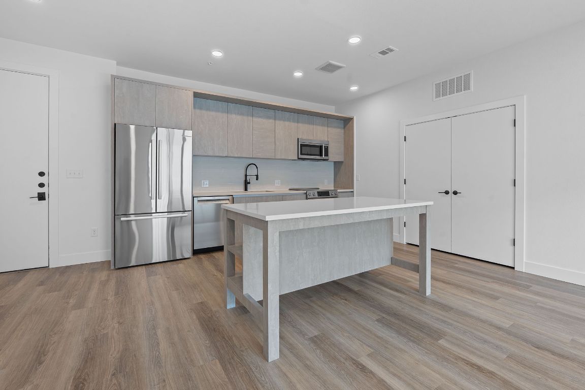 a kitchen with stainless steel appliances a sink cabinets and wooden floor