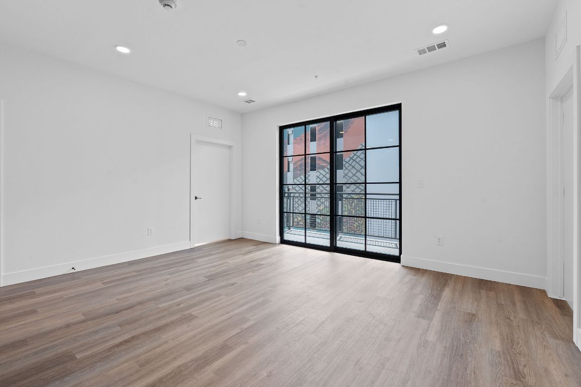 4315 South Congress Avenue, Unit 313 Austin, TX 78745 - Photo 4 of 38 a view of an empty room with wooden floor and a window