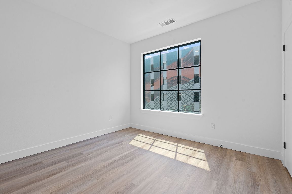 4315 South Congress Avenue, Unit 313 Austin, TX 78745 - Photo 8 of 38 an empty room with wooden floor and windows