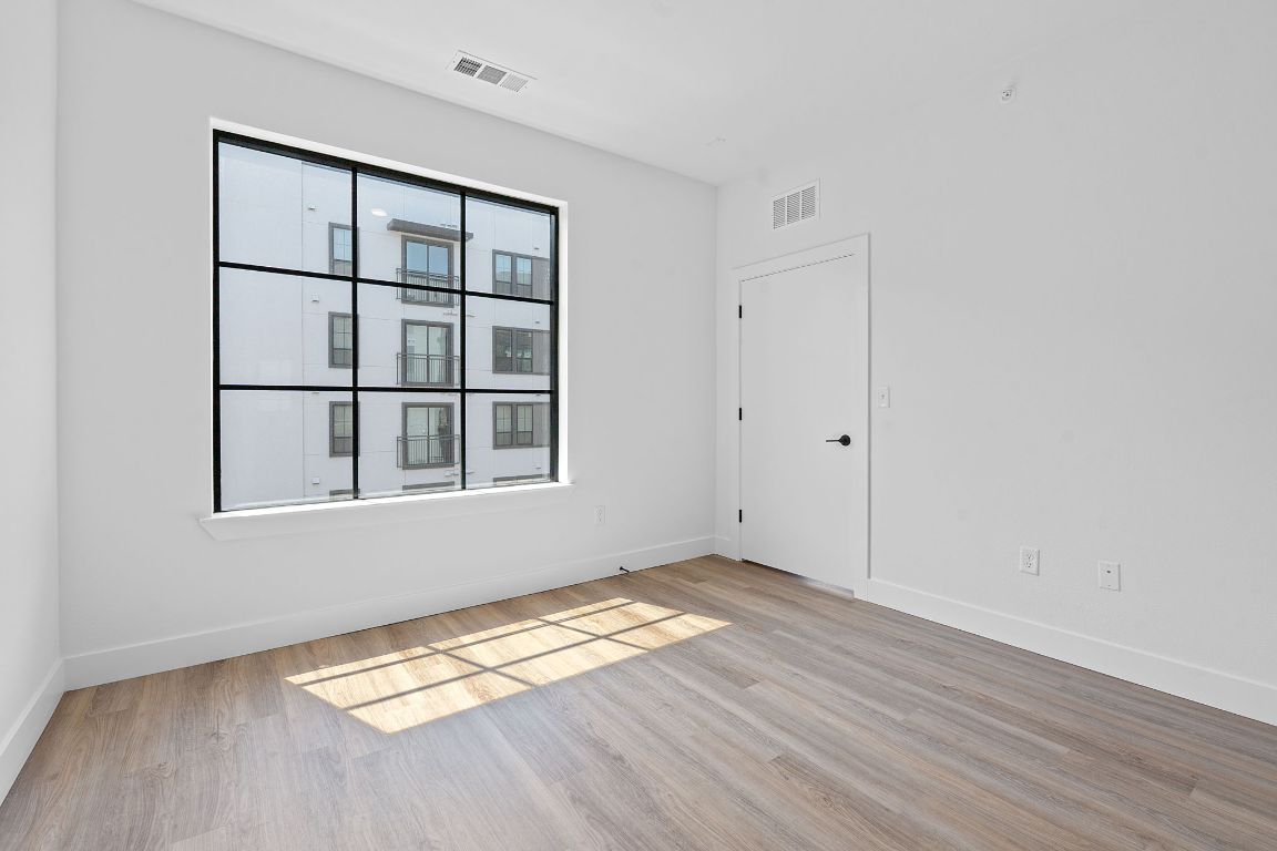 4315 South Congress Avenue, Unit 313 Austin, TX 78745 - Photo 9 of 38 a view of an empty room with wooden floor and a window