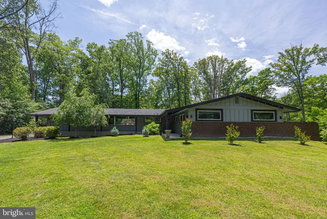 a view of a house with a yard and large trees
