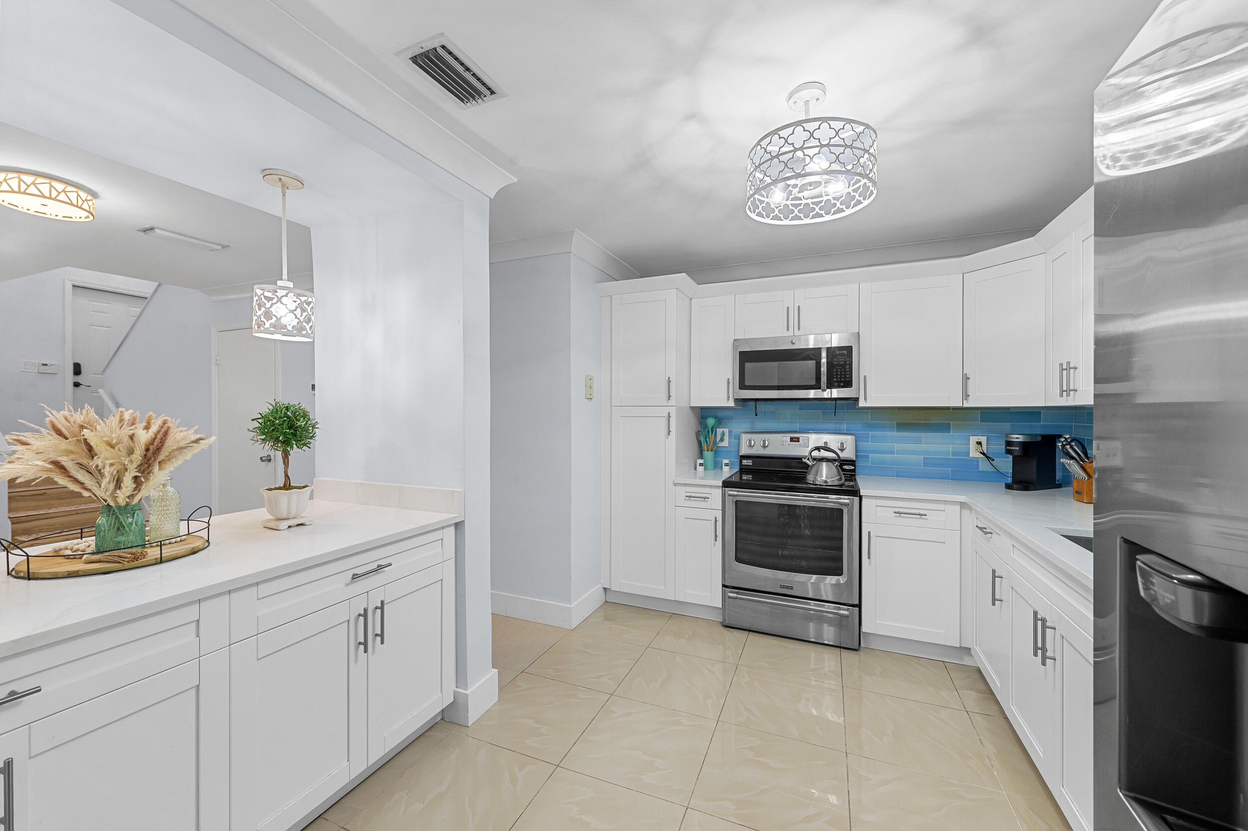 6548 Via Regina Boca Raton, FL 33433 - Photo 12 of 41 a kitchen with white cabinets and stainless steel appliances