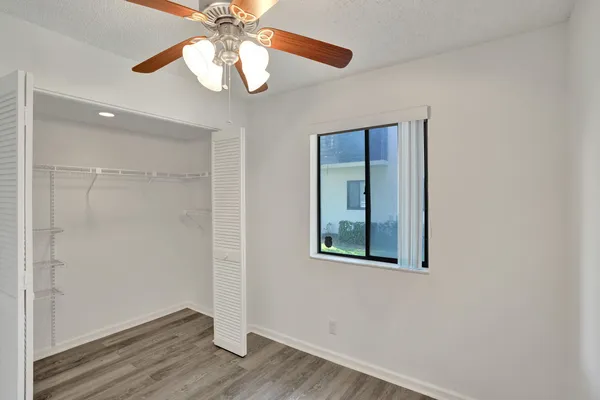 an empty room with wooden floor fan and windows