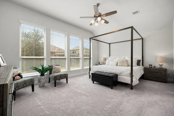 a bedroom with a bed couch and windows