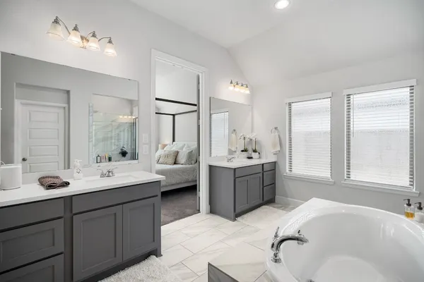 a bathroom with a tub double sink and mirror