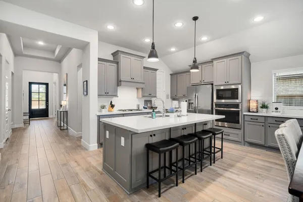 a kitchen with stainless steel appliances kitchen island granite countertop a stove a sink dishwasher a refrigerator and a dining table with wooden floor