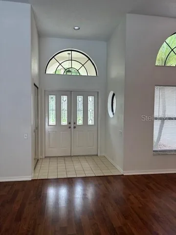 an empty room with wooden floor mirror and windows