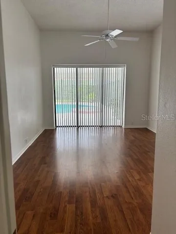 an empty room with wooden floor fan and window