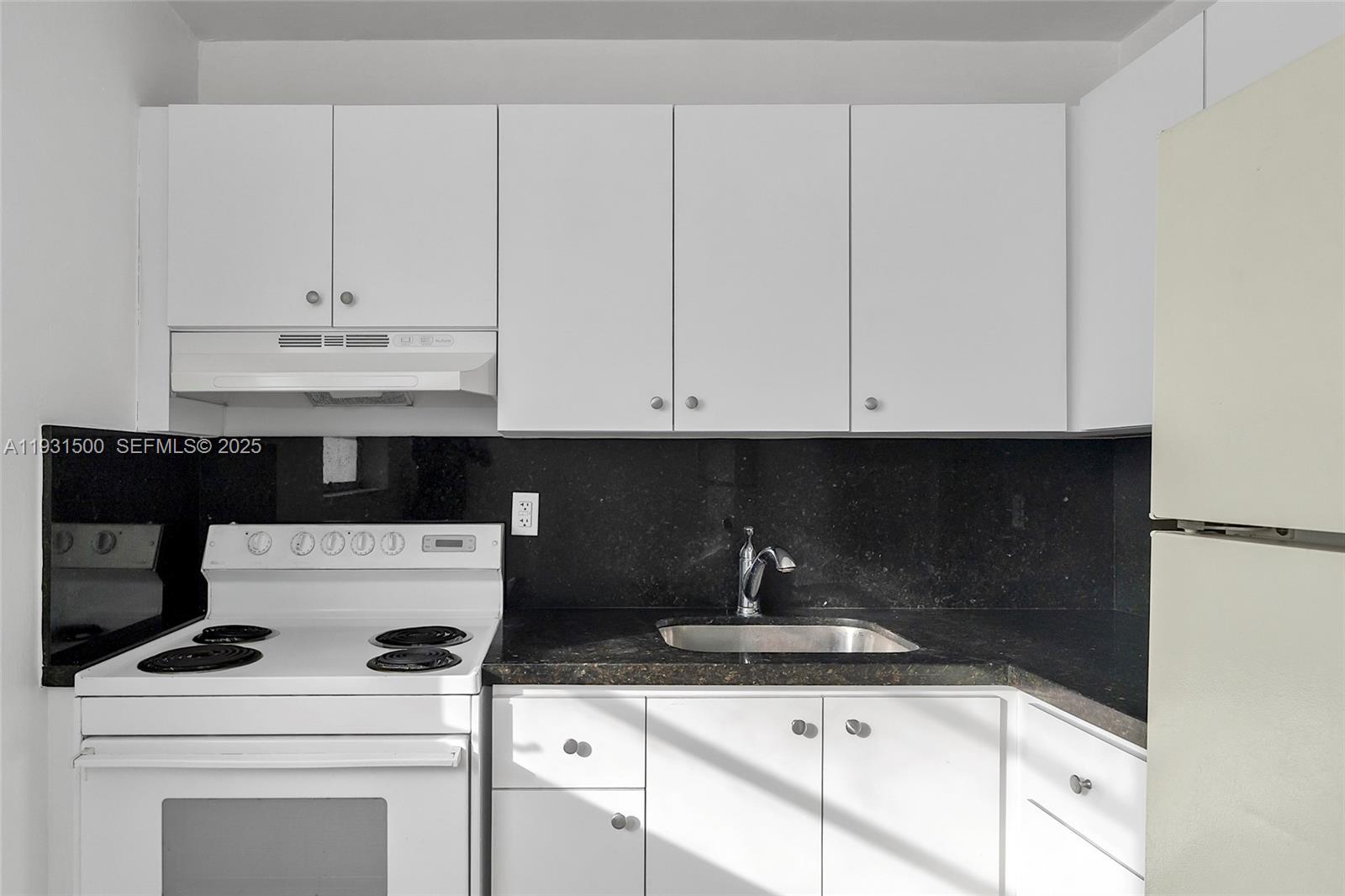 644 Southwest 10th Street, Unit 5 Miami, FL 33130 - Photo 11 of 26 a kitchen with granite countertop white cabinets and white appliances