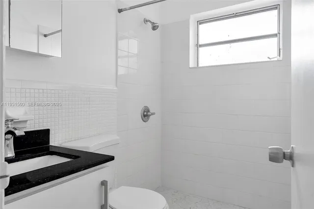 a bathroom with a granite countertop toilet a sink and shower
