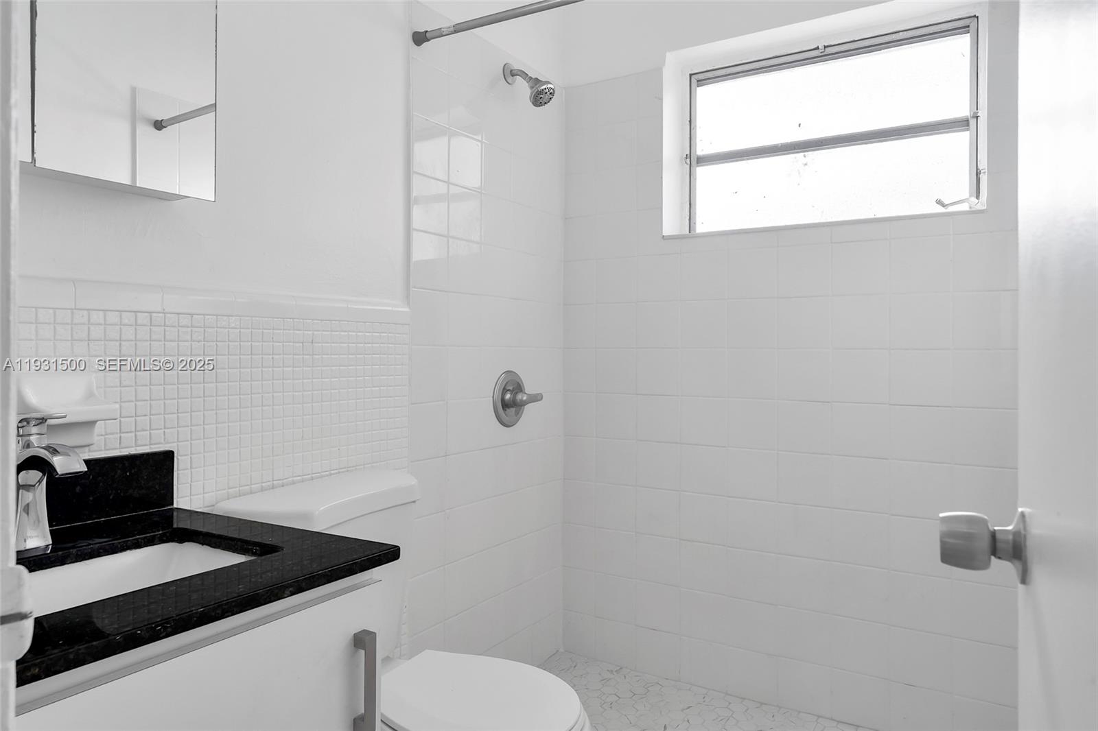 644 Southwest 10th Street, Unit 5 Miami, FL 33130 - Photo 16 of 26 a bathroom with a granite countertop toilet a sink a window and vanity