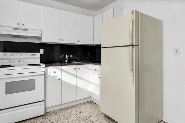 a kitchen with a refrigerator sink and cabinets