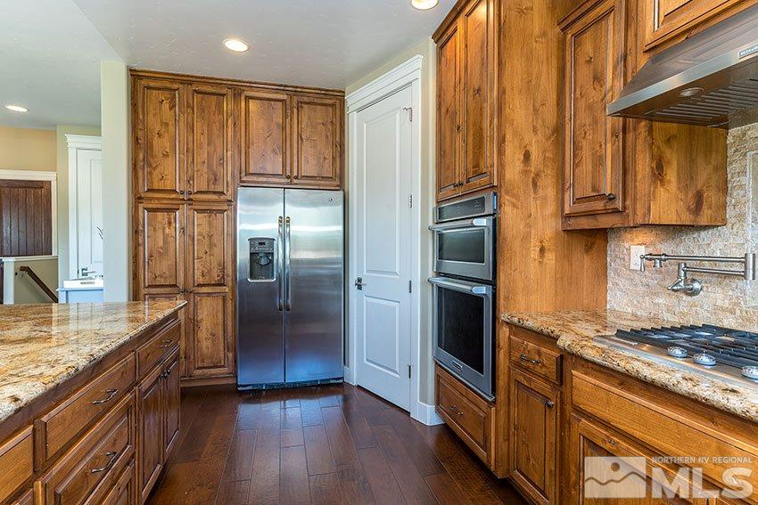 1195 Belford Road Reno, NV 89509 - Photo 16 of 35 a kitchen with kitchen island granite countertop a refrigerator and wooden cabinets