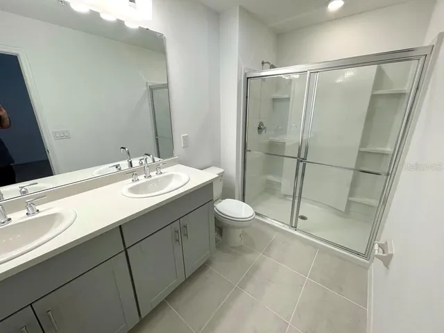 a bathroom with a double vanity sink toilet and shower