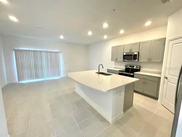 a kitchen with kitchen island a sink a stove a microwave and a refrigerator