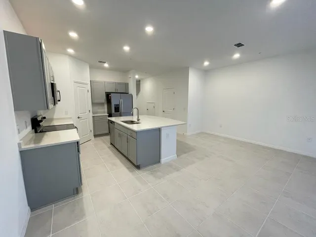 a large kitchen with a sink stainless steel appliances and counter space