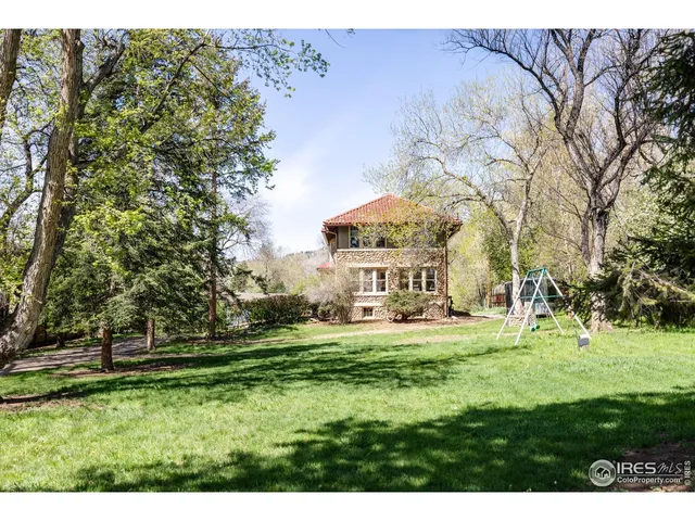a view of a house with a big yard and large trees