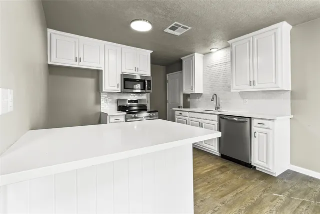 a kitchen with granite countertop a refrigerator and a stove top oven