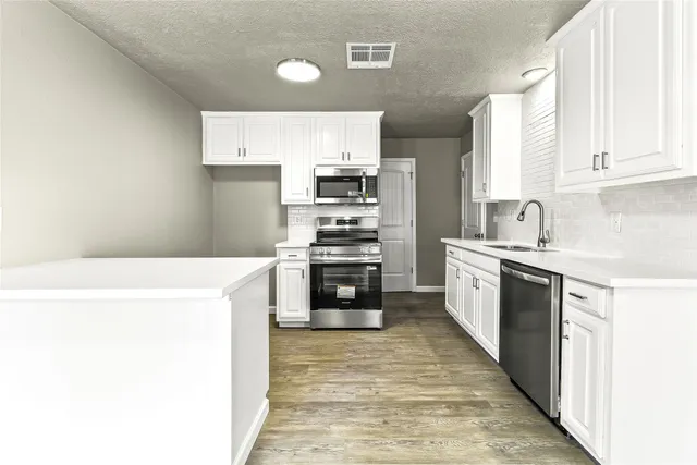 a kitchen with stainless steel appliances granite countertop a sink a stove and a wooden floors