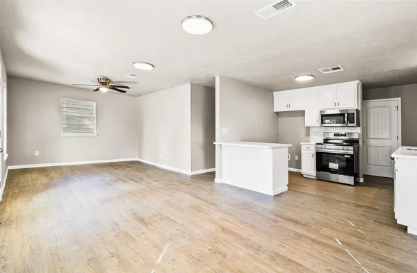 a view of an empty room with a window and wooden floor