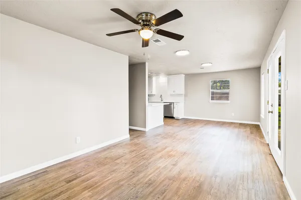 a view of an empty room with wooden floor and a window