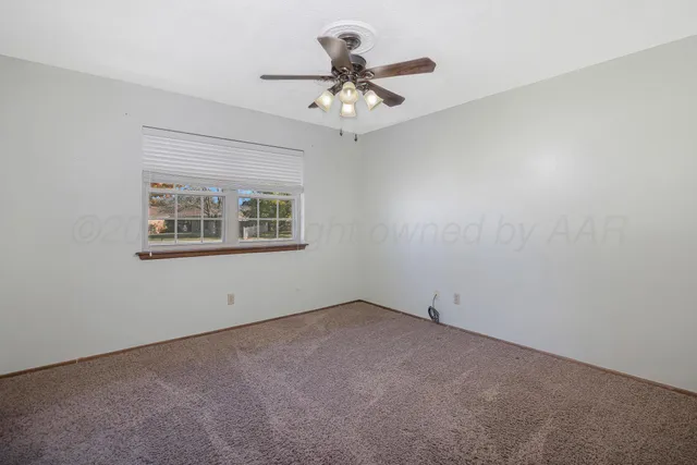 an empty room with a chandelier fan and windows