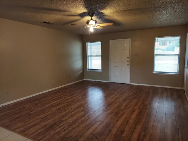 a view of an empty room with wooden floor and a window