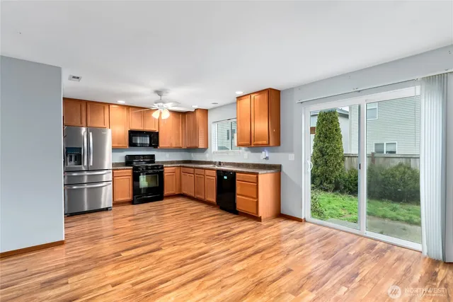 a kitchen with stainless steel appliances kitchen island granite countertop a refrigerator a stove a sink dishwasher a oven with wooden cabinets and wooden floor