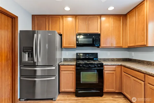 a kitchen with stainless steel appliances granite countertop a refrigerator a stove a sink and a microwave